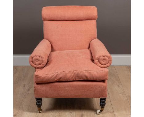 With a bolster topped back, circular arms, and on turned front legs with ceramic castors. Upholstered in a peach coloured fab