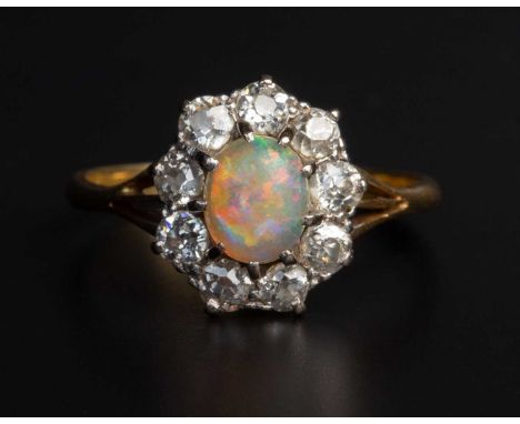 The oval cabochon opal claw set within a ring of nine single-cut diamonds, the band stamped 18ct goldopal appox 7mm long x 6m