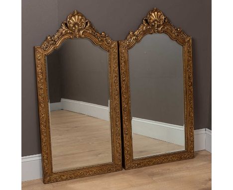 Each with arched tops surmounted by a scallop, flanked by foliate scrolling motifs and the beaded slips enclosing a mirror pl