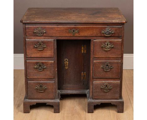 With a caddy top above an arrangement of seven fitted drawers with brass swan neck handles, surrounding a recessed cupboard, 