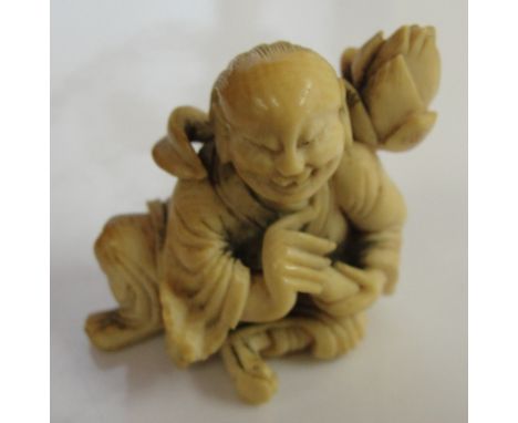 A Meiji period ivory Netsuke of a kneeling man and peach blossom