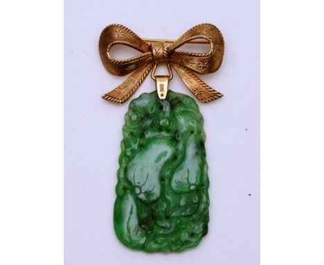 A Chinese jade pendant, mounted on 9ct gold brooch in the form of a bow, the green jade pendant carved with pierced foliate d