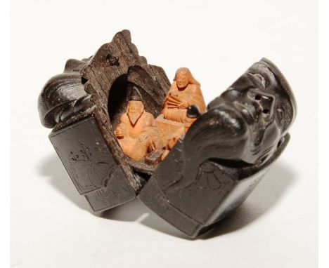 A 19th century Japanese ebony and sandalwood Netsuke signed Masamitsu, the top carved with two face profiles, enclosing three