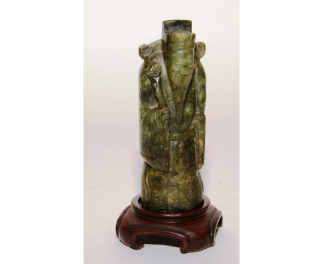 A 19th century Chinese green jade figure of a dignitary, raised on wood stand, 17cm high