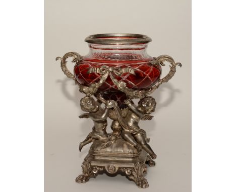 A 19th century Continental cast metal and ruby glass centrepiece, the bowl held by two winged cherubs on square base terminat