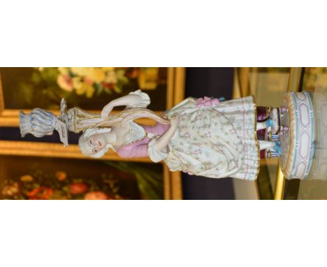 A Continental porcelain figural candlestick, in the form of a female holding cornucopia shaped vase, in pink, blue, cream and