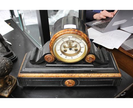 A late 19th Century black slate and marble eight day mantle clock, having a white enamelled dial, round head with brackets to