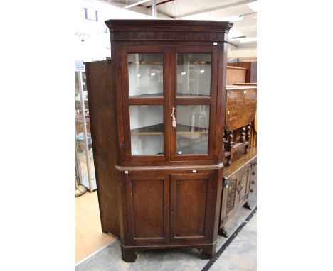 A 19th Century and later oak corner cupboard, moulded cornice, above two panel glazed doors opening to shelves, on a two pane