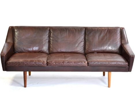 A 1970s Danish Brown Leather Three Seater Sofa, with squab cushions, square form arms and raised on wooden tapering legs, 175