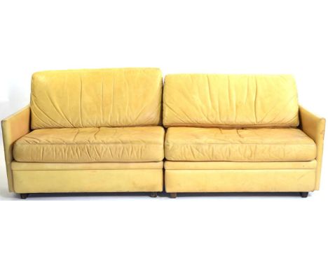 A 1970s Danish Dux Light Tan Leather Sofa, in two sections, with rounded back support and squab cushions, raised on block sup