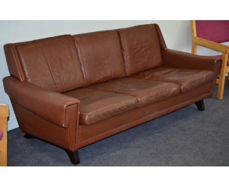 A 1970s Danish Brown Leather Three Seater Sofa, of curved form with square form legs, with six squab cushions, raised on tape