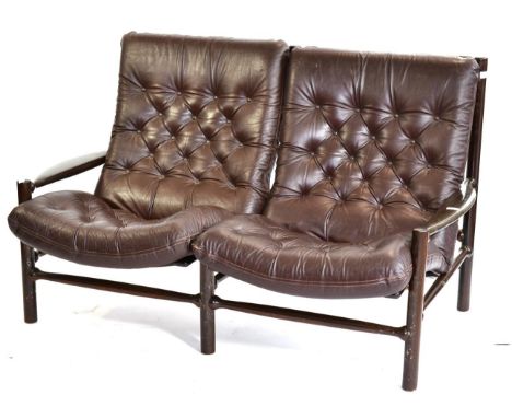 A 1970s Danish Brown Leather Two Seater Sofa, with four buttoned squab cushions, rounded arms and legs, 145cm by 87cm by 88cm