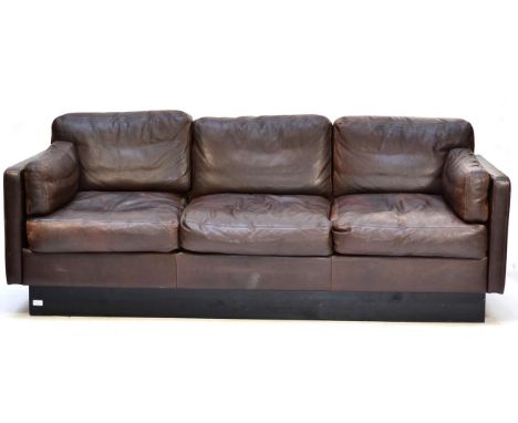 A 1970s Danish Brown Leather Three Seater Sofa, with squab cushions and square form armrests, raised on a plinth base, 202cm 