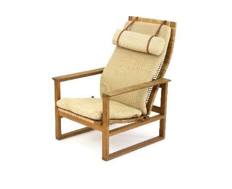An oak framed reclining armchair, possibly Danish with caned seat and leather strapped calico seat cushion