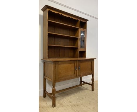 An oak dresser, circa 1930's, the raised back with three height shelf rack flanked by lead glazed cabinet, two cupboards to b