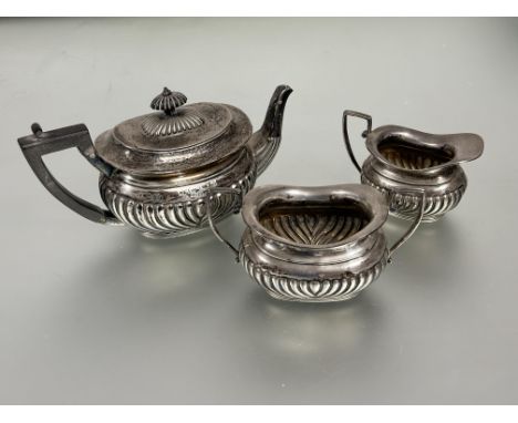 A London silver three piece individual morning tea service of oval half lobbed design the tea pot with ebonized finial and ha