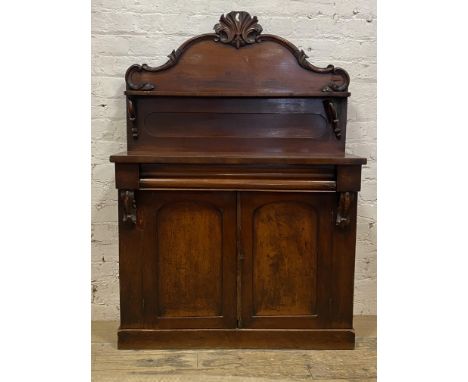 A Victorian mahogany chiffonier, the raised and floral carved back with open shelf above a drawer and two arch panelled cupbo