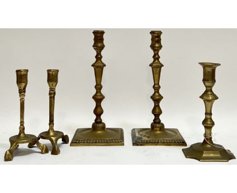 A group of eighteenth century brass candlesticks comprising a small pair tripod pair, a pair raised on square bases, and an a