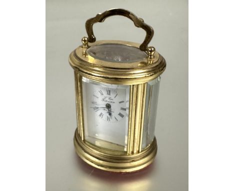 A miniature L'Epee french oval four glass brass table clock with brass handle to top and white enamel dial and foman numerals
