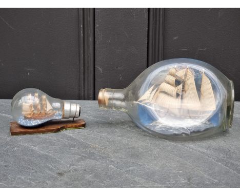 A vintage novelty ship in 'Dimple' bottle,&nbsp;20cm wide; together with another light bulb example. (2) 