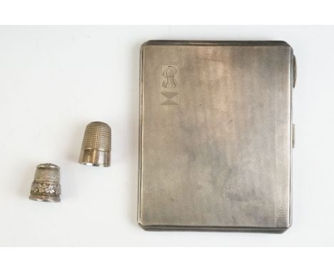 A fully hallmarked sterling silver cigarette case with engine turned decoration together with tow silver thimbles. 