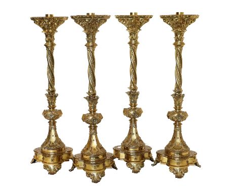 A Set of Four Gilt-Bronze Candle Stands, in Renaissance style, the leaf-sheathed shaped circular stands on wrythen fluted col