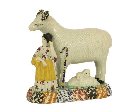 A Yorkshire Prattware Sheep Group, circa 1800, as a shepherdess standing beside an oversized ram, two lambs at their feet, on