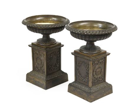A Pair of Regency-Style Bronze Urns, late 19th century, of shallow fluted campana form on square section columns cast with cl