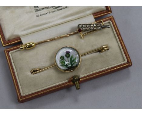 An early 20th century novelty yellow metal, diamond and gem set cricket bat and stumps stick pin and a bar brooch with thistl