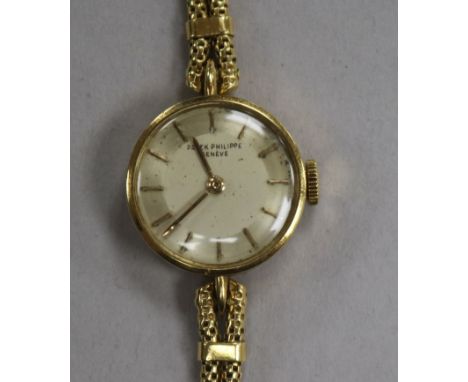 A lady's 18ct gold Patek Philippe manual wind wrist watch, with baton numerals, on an associated 18ct gold twin strand bracel