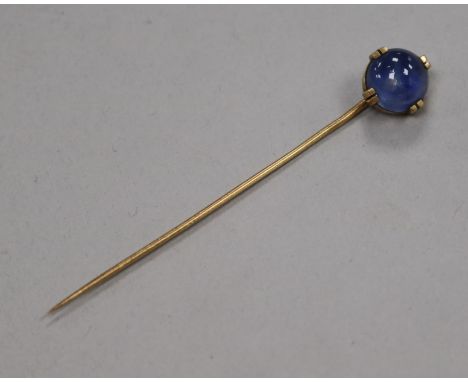 A yellow metal and cabochon star sapphire stick pin, 69mm.