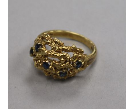 A 1960's 18ct gold and sapphire set pierced 'nugget' ring, size M.