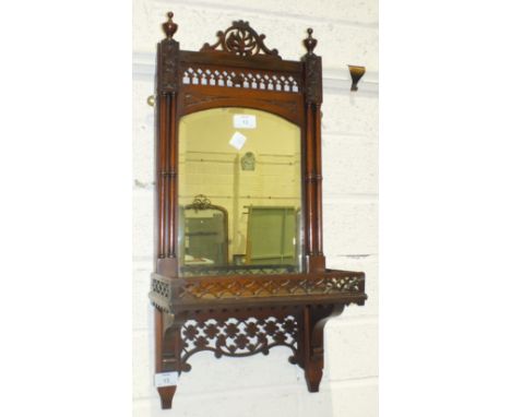 A late-19th/early-20th century walnut-framed hall mirror fitted with a shelf and pierced decoration, 66cm long, 29.5cm wide.