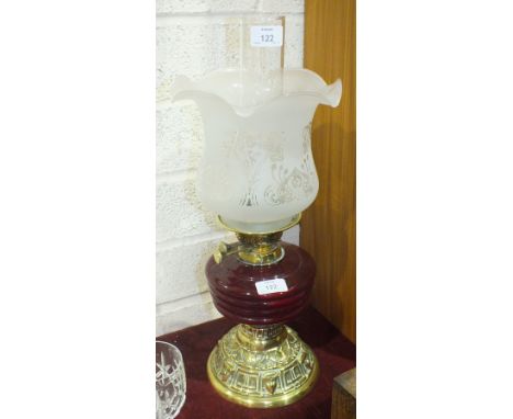 An oil lamp, the red glass reservoir on short column and circular brass base, with raised decoration, etched clear and opaque