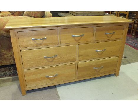 A modern light oak chest of three short and four long drawers with brushed handles, 138cm wide, 77cm high, 42.5cm deep.