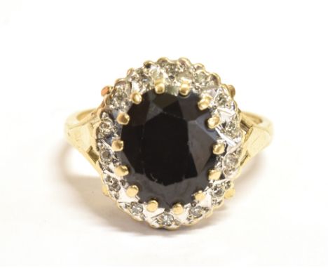 A 9ct GOLD SAPPHIRE CLUSTER RING The oval faceted sapphire set in white gold with clear stone accents on a yellow gold shank 