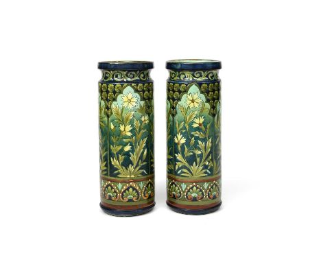 A pair of Doulton Lambeth Faience 'Persian' cylinder vases by LCM, shouldered form, painted with white flower panels in archi