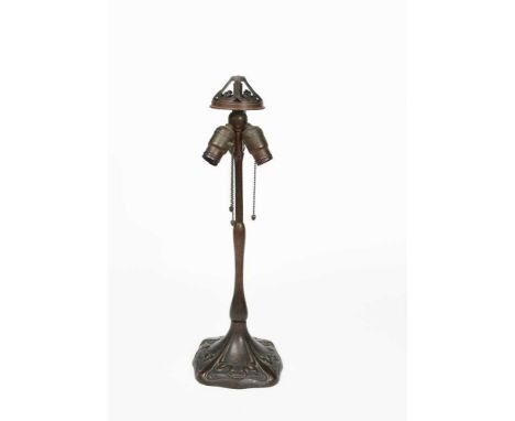 A Handel patinated metal lamp base, the flaring square section base cast in low relief with scrolling ribbon panels, cylindri