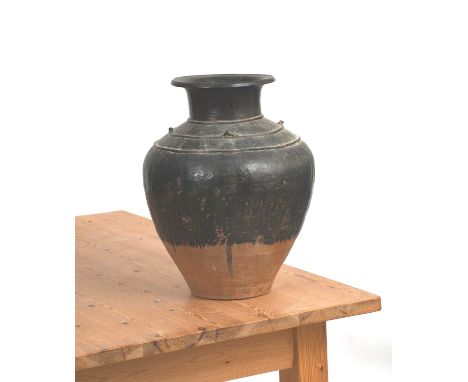 A large south-east Asian baluster vase, shouldered form with four applied loop handles and raised bands, glazed from neck to 