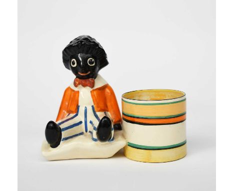 'Golly' a rare Clarice Cliff Bizarre pen-holder, modelled as a toy golly seated next to a cylindrical pen holder, printed fac