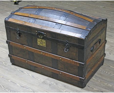 A 19th Century wooden metal and leather bound domed trunk with leather carry handles.  