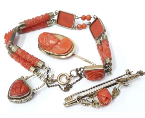 A suite of yellow metal and carved coral jewellery comprising a bracelet, a brooch and stick pin, unmarked, gross wt. 26.4g. 