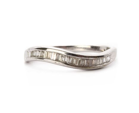 A 9ct white gold diamond half eternity ring, with a row of baguette cut diamonds channel set to the undulating head, to a pla