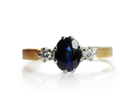 An 18ct gold sapphire and diamond ring,  a central oval mixed cut sapphire flanked by two round brilliant cut diamonds, all c