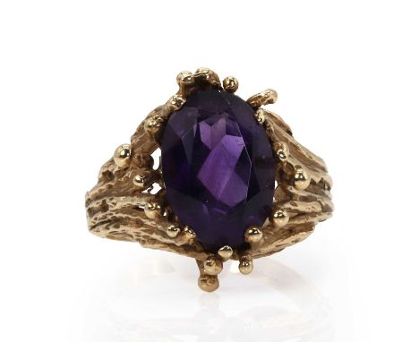 An abstract design amethyst ring,  with an oval cut amethyst, 10mm x 14mm, claw set to a loose cluster of spatulate wires, th