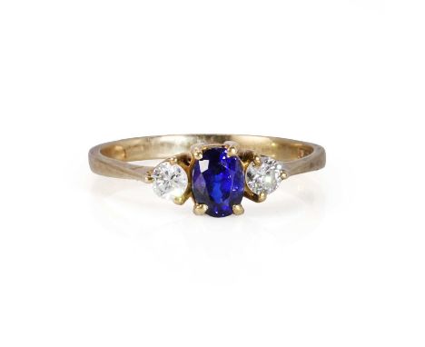 A 9ct gold sapphire and diamond ring,  with an oval mixed cut sapphire claw set to the centre, flanked by a round brilliant d