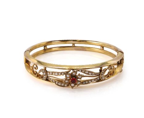 An Edwardian gold split pearl hinged bangle, the openwork bangle centring on a paste and split pearl set flowerhead, with sim