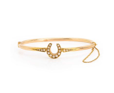 An early 20th century gold split pearl horseshoe bangle, with graduated split pearls, all grain set to a central horseshoe an