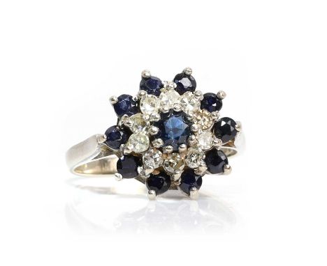 An 18ct white gold sapphire and diamond cluster ring,   with a central round cut sapphire, to a surround of eight cut diamond