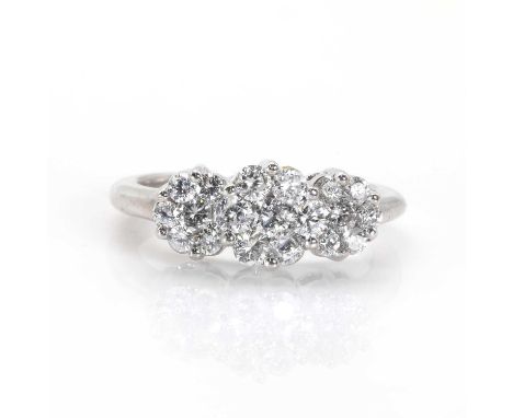 A white gold diamond set triple floral cluster ring,  designed as three graduated flower heads, each comprising a cluster of 